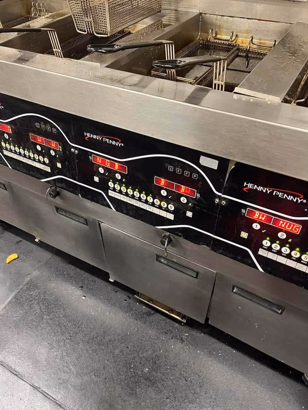Commercial stainless steel Henny Penny deep fryer with multiple baskets and digital control panels.